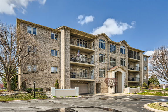 Front view of a multi-story brick apartment building with balconies.