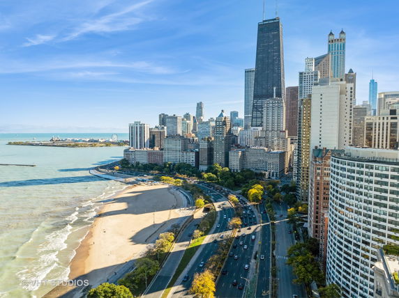 Panoramic view of a city skyline with tall buildings near a beach and water.