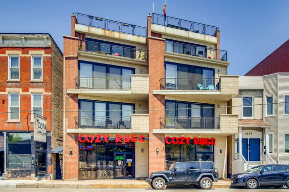 Front view of a multi-story building with balconies and a commercial space on the ground floor.