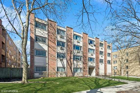 Front view of a multi-story apartment building with numerous windows and a central entrance.