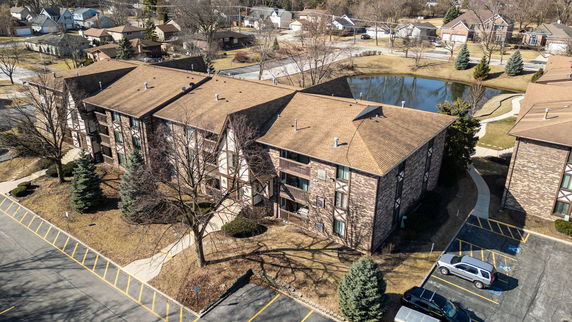 Aerial view of a multi-story apartment building with brick walls and pitched roofs.