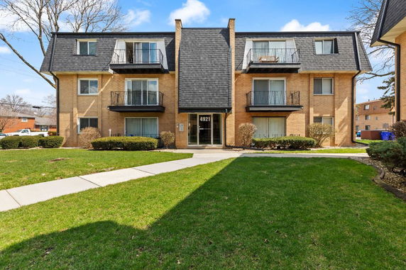 Front view of a three-story apartment building with a sloped roof and balconies.