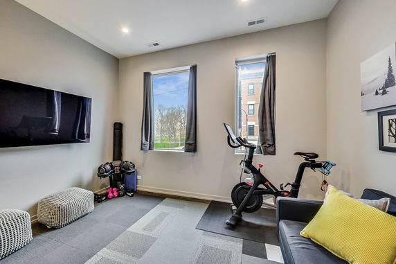 Room with exercise equipment including a stationary bike and dumbbells.