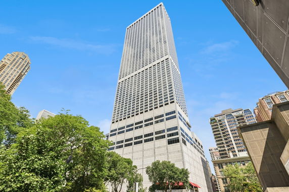 Front view of a tall skyscraper with a grid-like window pattern.