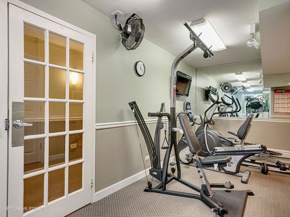 Indoor gym area with exercise equipment and mirrored wall.
