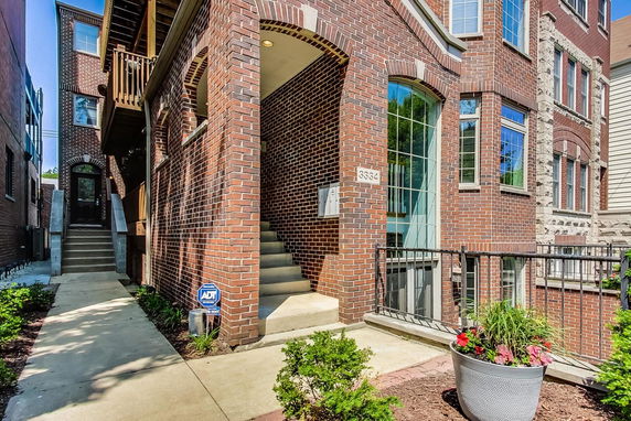 Front view of a multi-story brick building with stairs leading to the entrance.