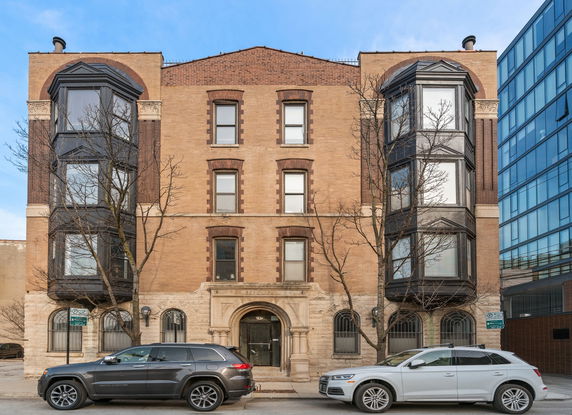 Front view of a multi-story brick building with large bay windows.