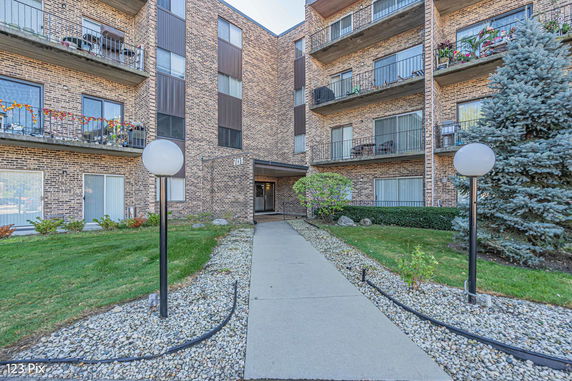 Front view of a multi-story brick apartment building with balconies.