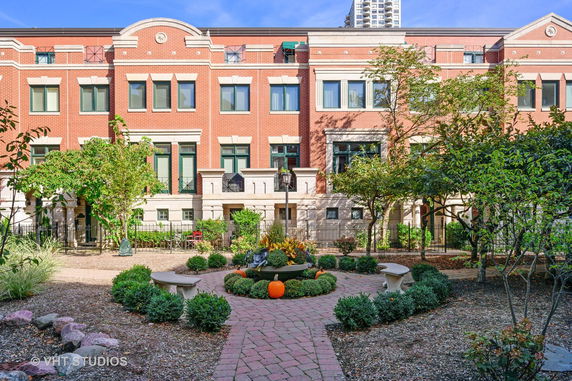 Front view of a red brick multi-story building with landscaped garden area.