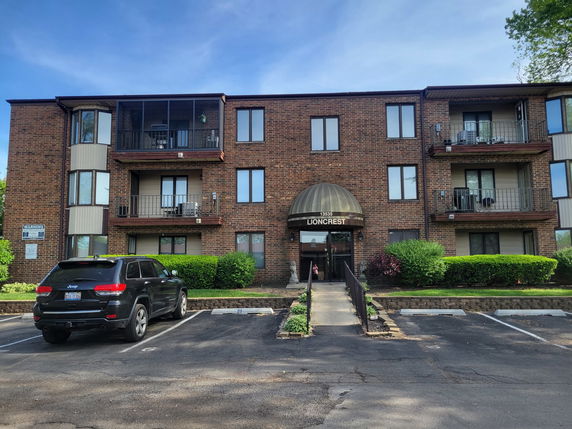 Front view of a three-story brick apartment building with balconies.