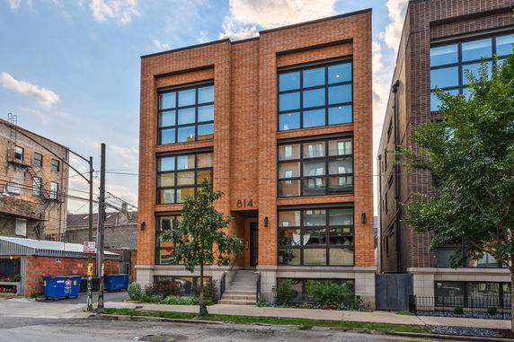 Front view of a modern multi-story brick building with large windows.