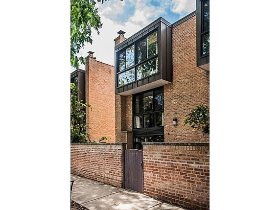 Front view of a modern multi-story brick building with large windows and a wooden gate entrance.