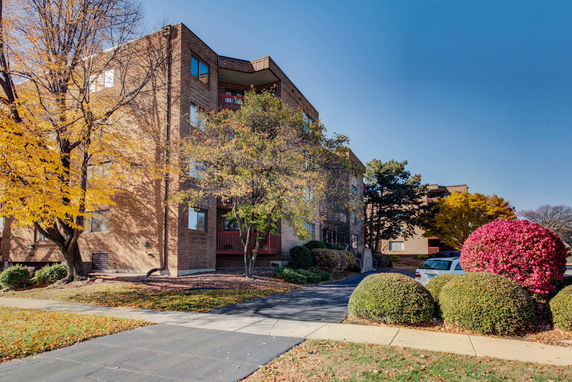 Front view of a multi-story brick building with surrounding trees and shrubs.