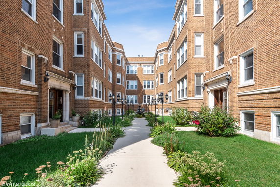Front view of a multi-story brick apartment building with a courtyard.