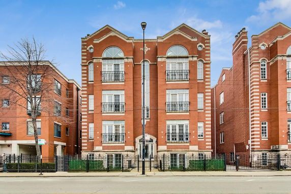 Front view of a multi-story brick building with arches over windows.