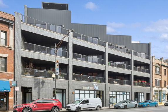 Front view of a multi-story building with balconies and brick facade.