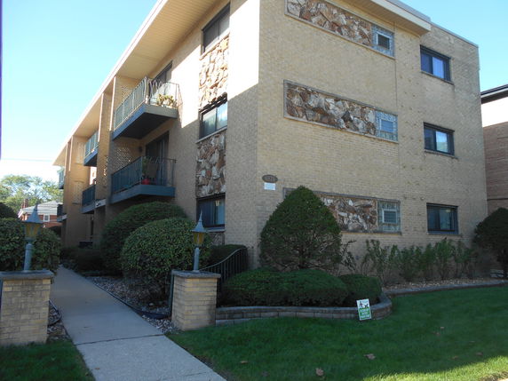 Front view of a multi-story apartment building with balconies and decorative stone accents.