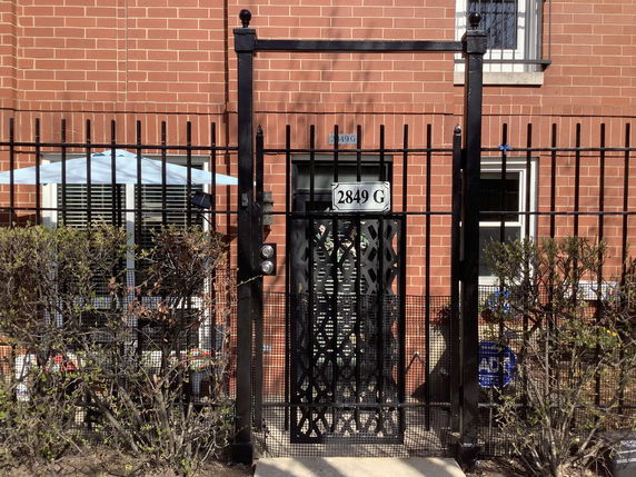 Front view of a brick building with a black metal gate and fence.