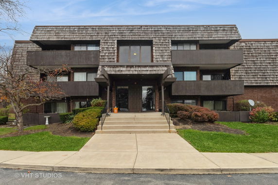 Front view of a multi-story brick building with a shingle-style roof and balconies.