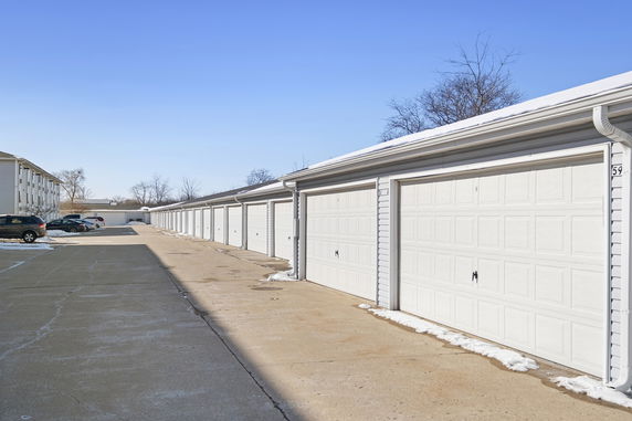 Outdoor parking area with multiple garages and parked cars.