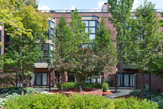 Front view of a multi-story brick building with trees and landscaping.