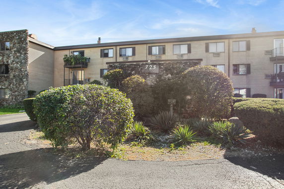 Front view of a three-story building with stone facade and some balconies.