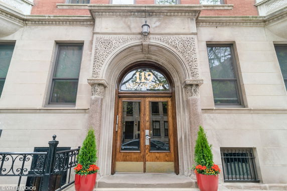 Front view of a building entrance with ornate arch and wooden door.