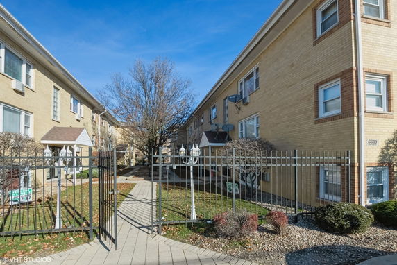 Front view of a two-story apartment building with a gated entrance.