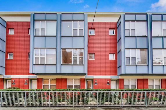 Front view of a modern multi-story residential building with red and blue facade.