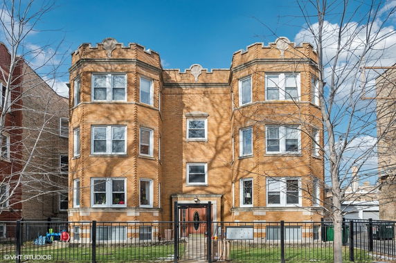 Front view of a three-story brick apartment building with multiple windows.