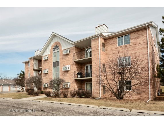 Front view of a multi-story brick apartment building with balconies.