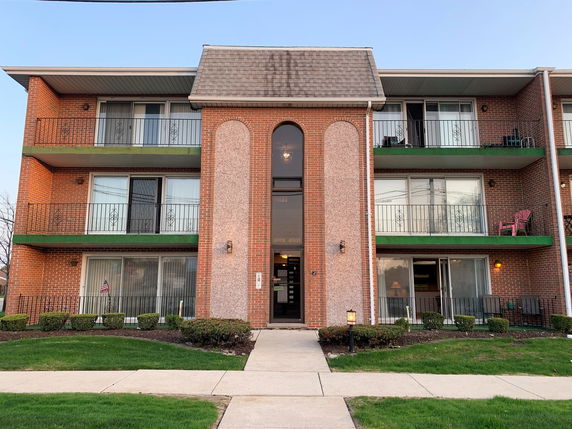 Front view of a three-story apartment building with balconies.