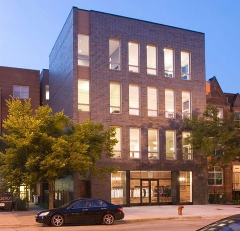 Front view of a multi-story brick building with large windows.