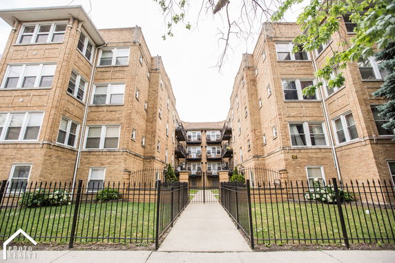 Front view of a multi-story brick apartment building with a central courtyard.