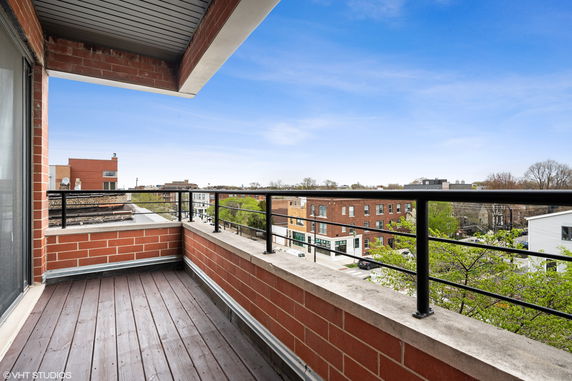 Balcony view overlooking rooftops and surrounding neighborhood buildings.