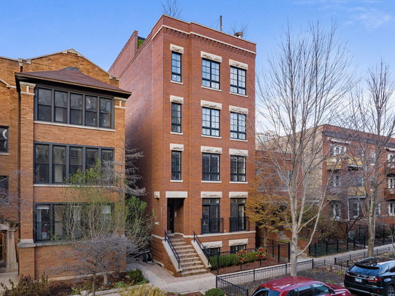Front view of a multi-story brick apartment building with stairs leading to the entrance.