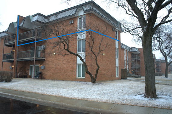Front view of a multi-story brick apartment building with balconies.