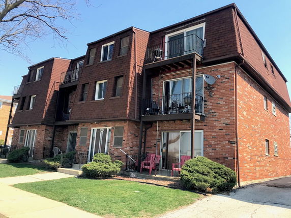 Front view of a multi-story brick apartment building with balconies.