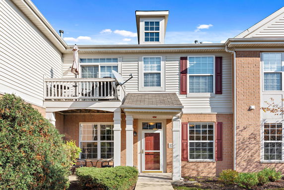 Front view of a two-story house with a small balcony and a red door.