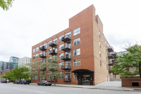 Front view of a multi-story brick apartment building with balconies.
