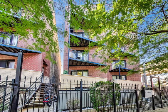 Front view of a multi-story brick apartment building with balconies.