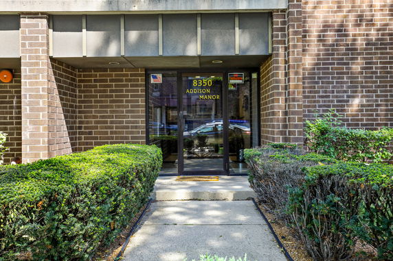 Front view of a building entrance with a brick facade and glass door.