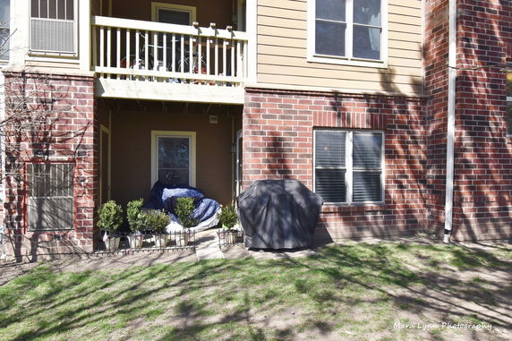 Front view of a brick apartment building with a patio and balcony.