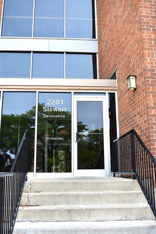 Front view of a building entrance with glass doors and brick exterior.