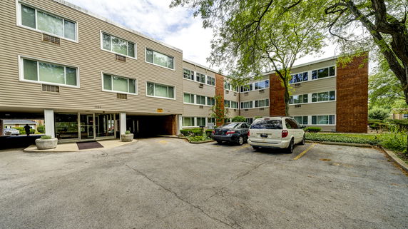 Front view of a multi-story apartment building with a parking area.