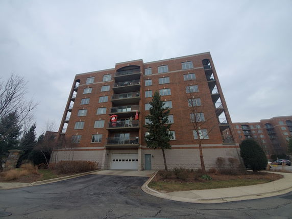 Front view of a multi-story brick apartment building with balconies.