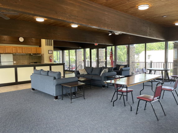 Interior view of a recreational area with sofas, tables, and a kitchenette.