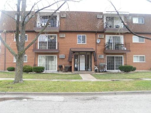 Front view of a three-story brick apartment building with balconies.