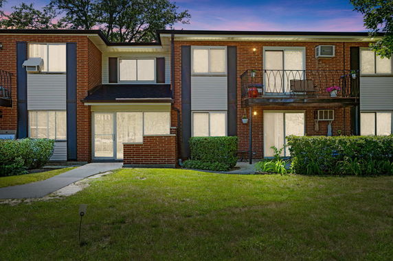 Front view of a two-story brick apartment building with balconies.