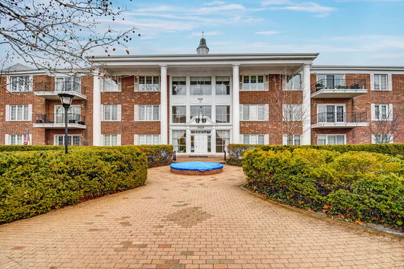 Front view of a multi-story brick building with balconies and white pillars.